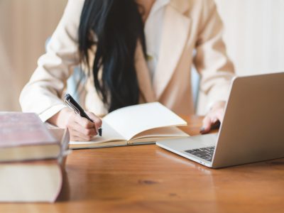 Mulher estudando com computador e caderno para uma pós graduação EAD.