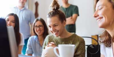 Alunos olhando para um computador e sorrindo