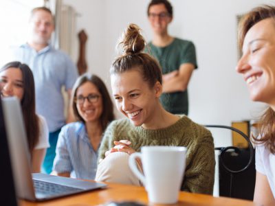 Alunos olhando para um computador e sorrindo