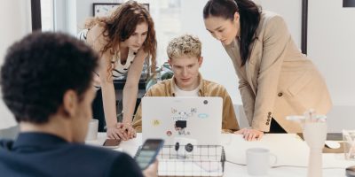 Grupo de jovens conversando com um computador ao redor de uma mesa